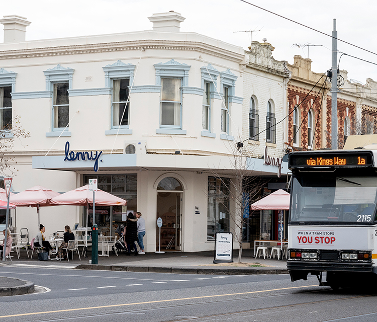 Melbourne tram travelling down road past corner restaurant