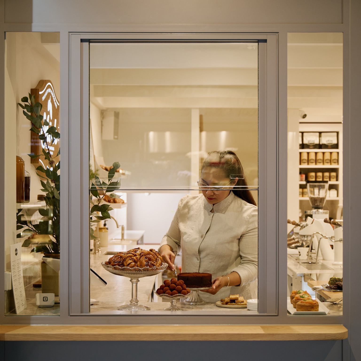 Window front of a shop with a woman serving chocolate cake.